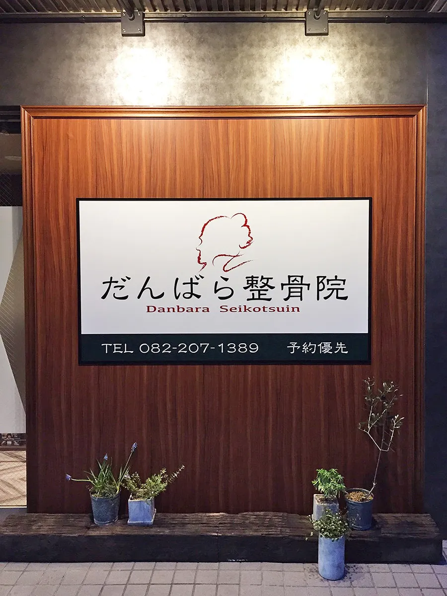 だんばら整骨院の看板。木目調の壁に掲げられた白い看板